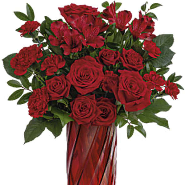 Tall bouquet of red roses, carnations, and alstroemeria in a red glass vase