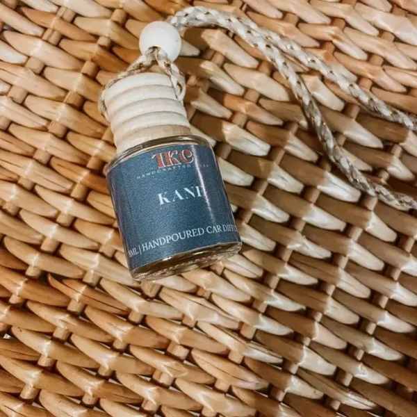 Small glass bottle of car diffuser hanging on woven straw background