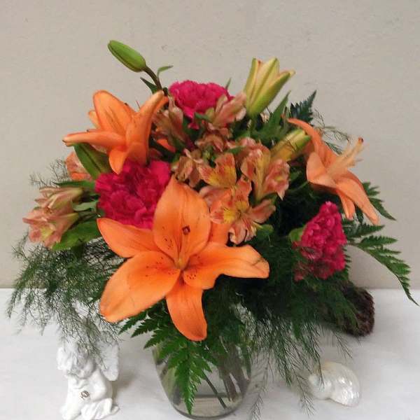 Orange lilies and pink carnations in a glass vase