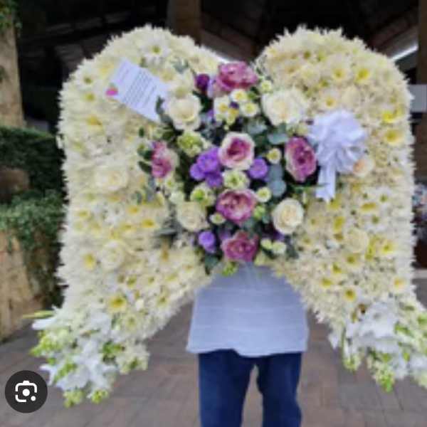 Large floral tribute shaped like angel wings with white and purple flowers