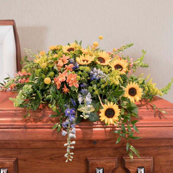 Colorful floral casket spray with sunflowers and mixed blooms