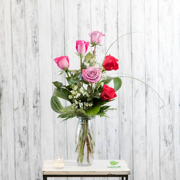 Pink and red roses arranged in a clear glass vase.