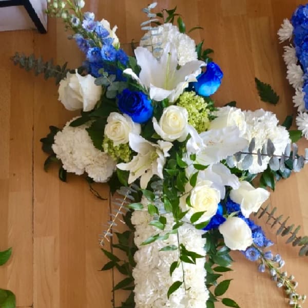 White and blue floral cross arrangement with roses and lilies