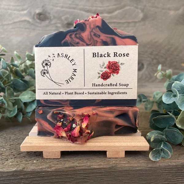 Two bars of black and pink rose soap on a small wooden stand