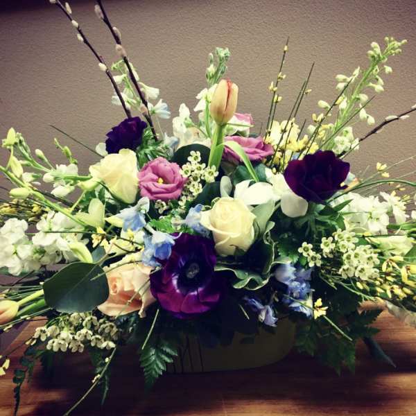 Low floral centerpiece with mixed roses and tulips in a container