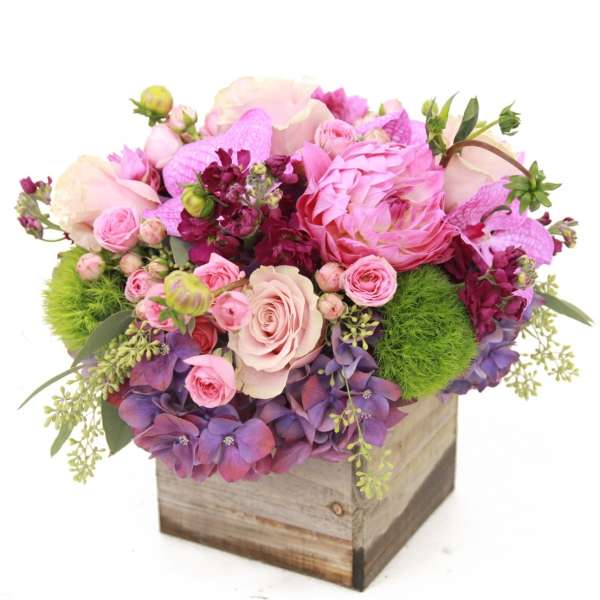 Pink and purple floral arrangement in a wooden box