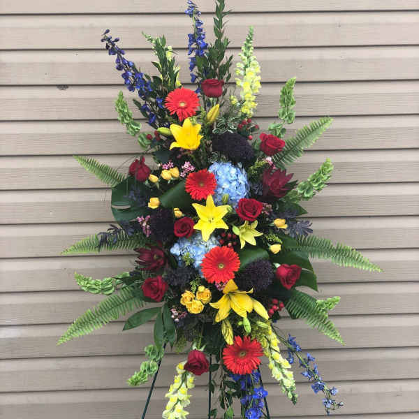 Tall standing floral spray with red, yellow, blue, and purple blooms