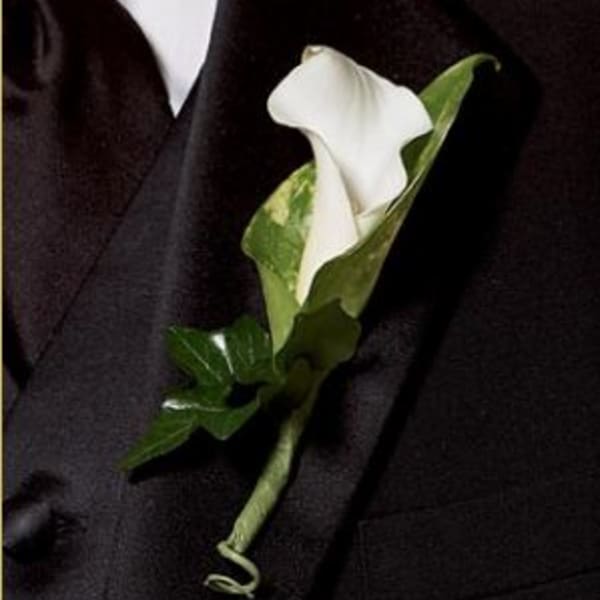 White calla lily boutonniere on a dark suit lapel