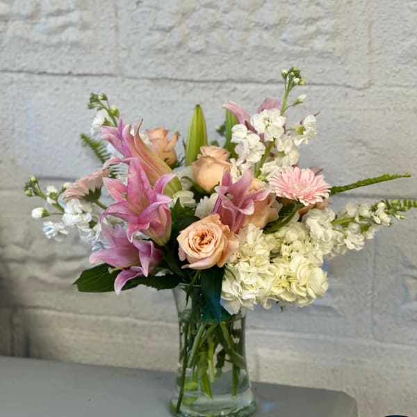 Pink and peach flowers arranged in a clear glass vase