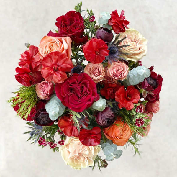 Round bouquet of red, pink, peach, and cream flowers