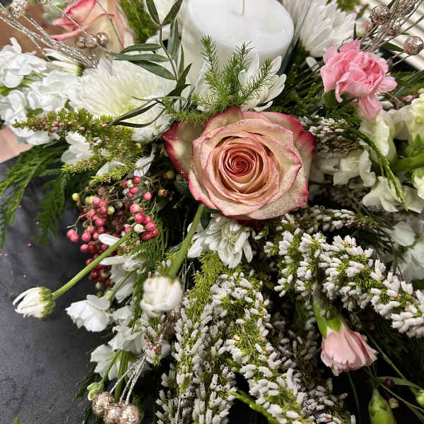 Floral centerpiece with a glass candle holder and pink rose