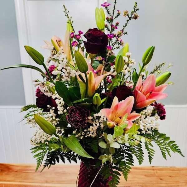 Tall mixed bouquet with pink lilies and dark roses in a vase