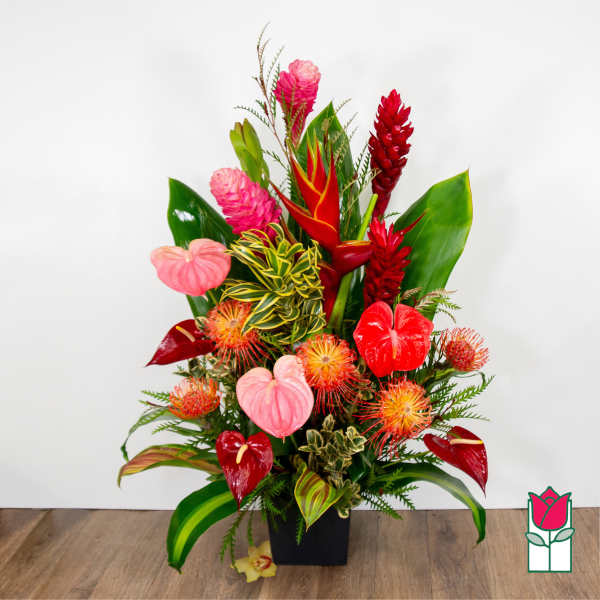 Tropical flower arrangement in a black vase with red and pink blooms