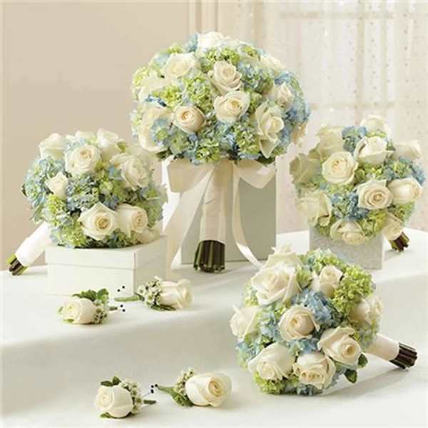 White rose bouquets with pale blue flowers and green accents on a table