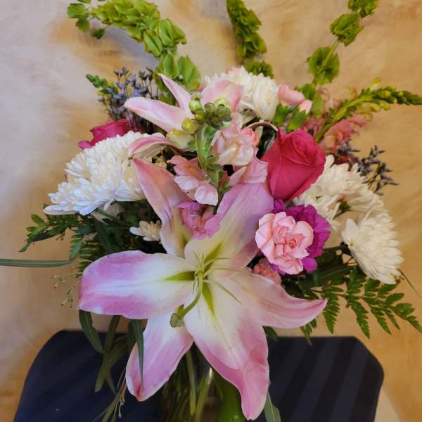 Pink lilies and roses with white chrysanthemums in a glass vase