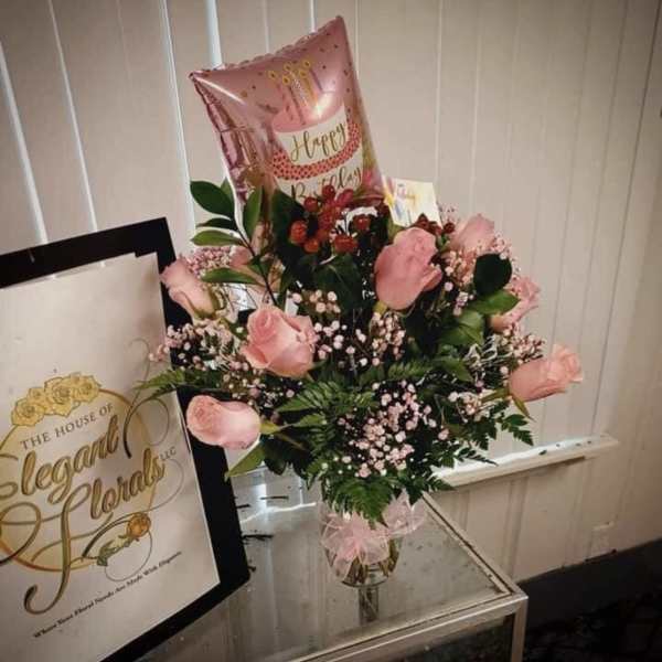 Pink rose bouquet in a glass vase with a birthday balloon and gift bag