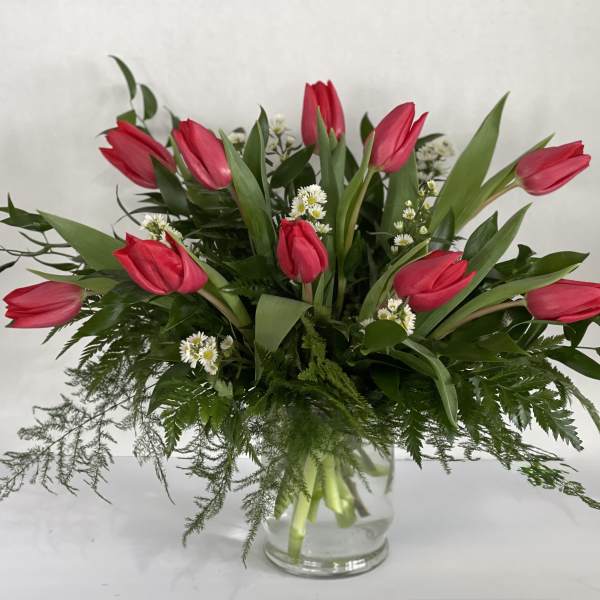 Pink tulips arranged in a clear glass vase with white filler flowers