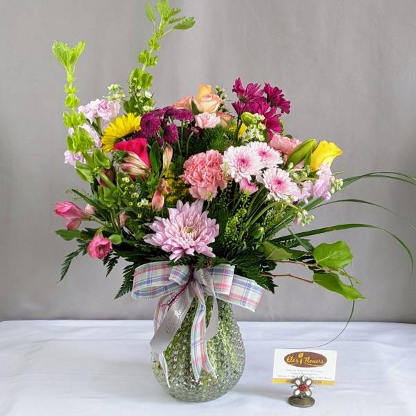 Mixed bouquet in a textured glass vase with a plaid ribbon