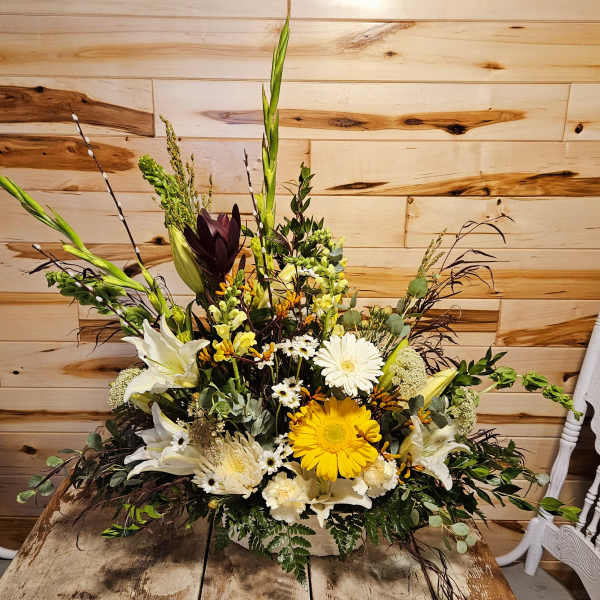 Tall mixed floral arrangement with white lilies, yellow gerbera daisies, and greenery