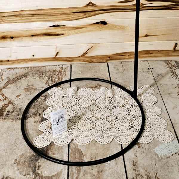 Black metal hanging stand with a circular base and hook top