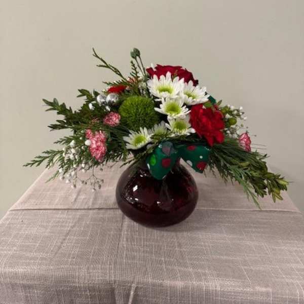 Red roses and white daisies in a round glass vase with a bow