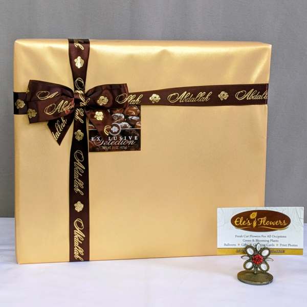 Large gold gift box with brown ribbon and a small card holder in front