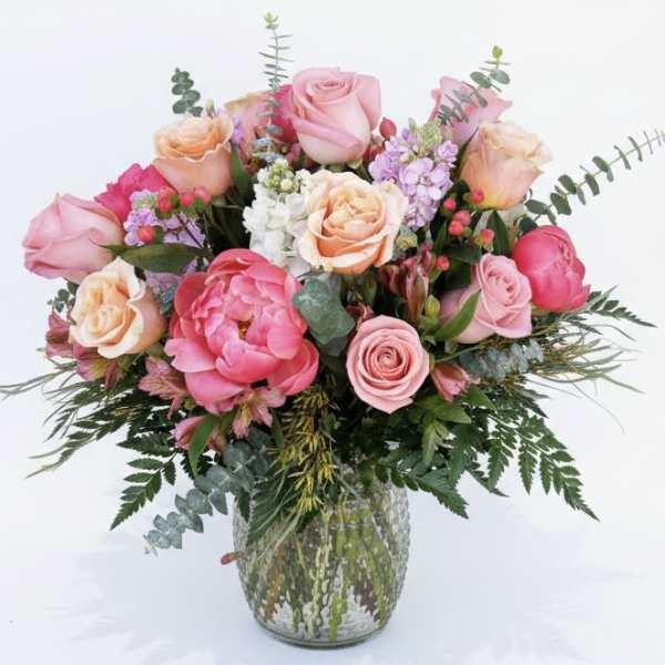 Pink and peach roses arranged in a glass vase