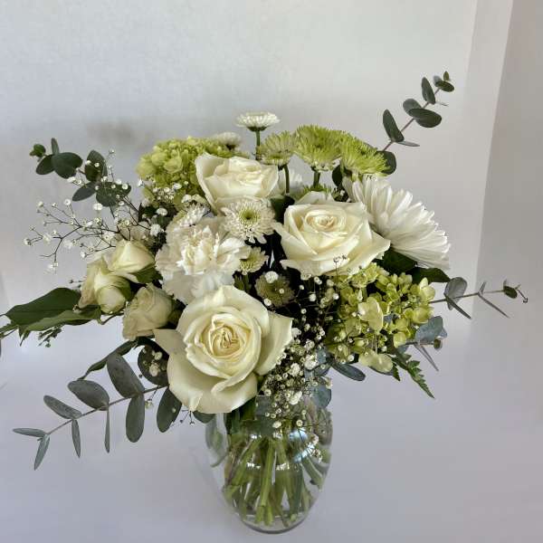 White roses and green chrysanthemums in a glass vase