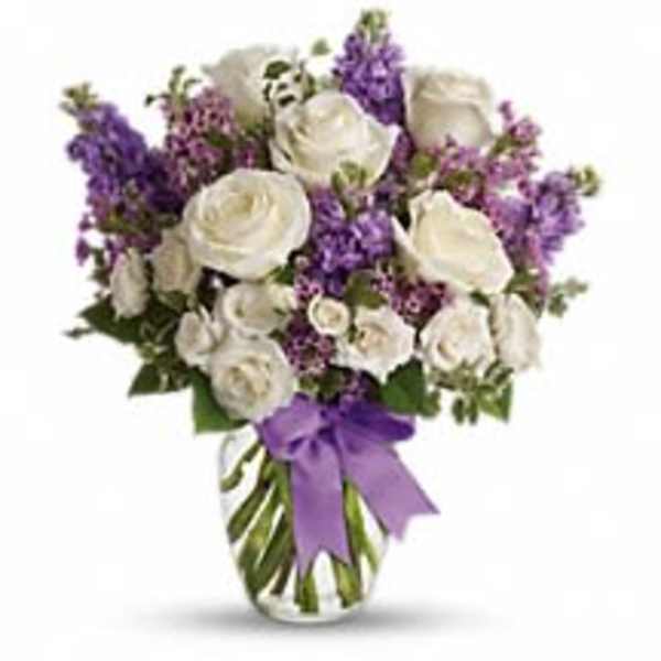 White rose and purple flower arrangement in a clear glass vase with a purple ribbon bow