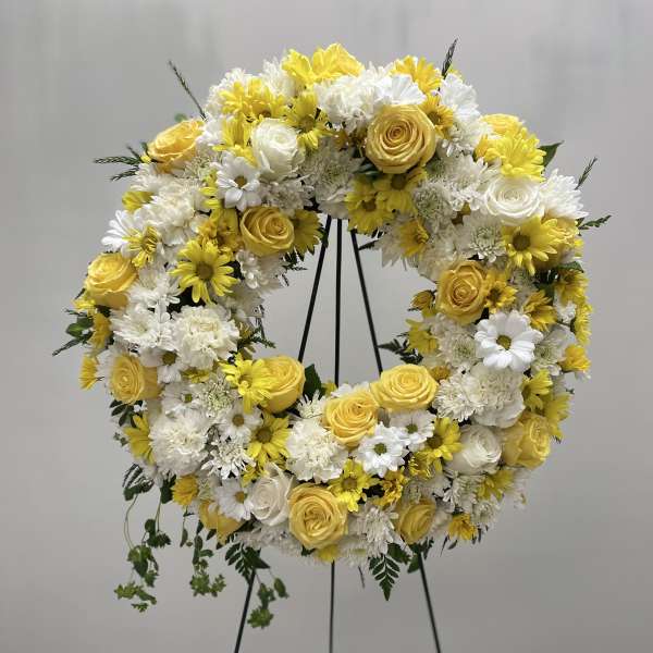 Yellow and white floral wreath on a black stand