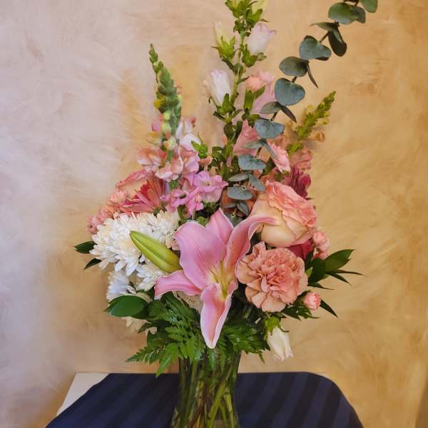 Pink lily and mixed pastel flowers in a glass vase