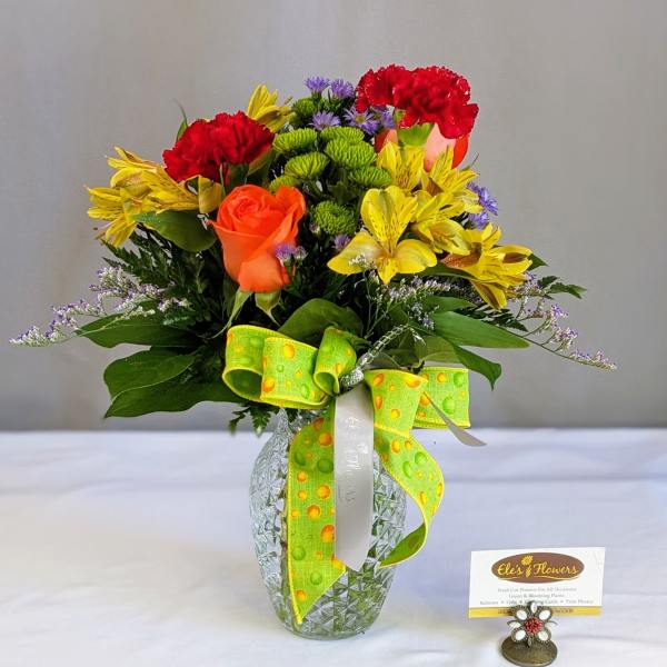 Mixed bouquet in a glass vase with red, yellow, and orange flowers