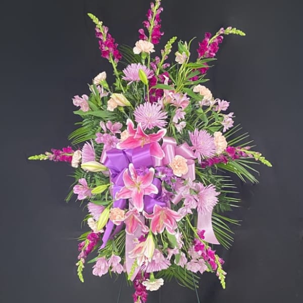 Pink and purple funeral spray with lilies and ribbon on an easel