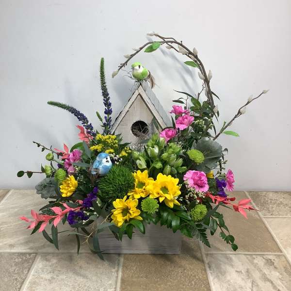 Colorful floral arrangement with a birdhouse and decorative birds