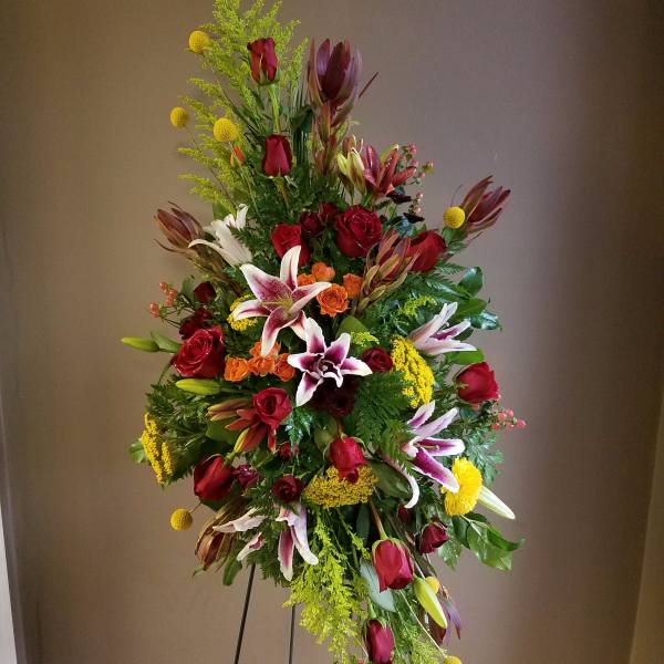 Tall standing floral spray with red roses, lilies, and yellow accents