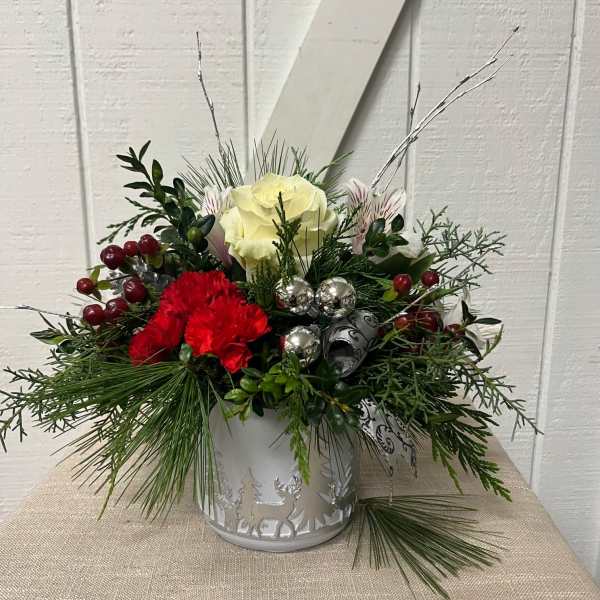 Holiday floral arrangement in a white metal container with red and white blooms