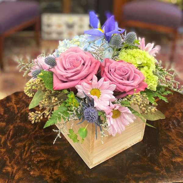 Pink roses and pastel mixed flowers arranged in a wooden box