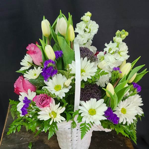 Basket arrangement of white daisies, pink roses, and tulips