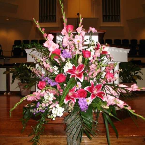 Large pink and white floral arrangement in a stone vase