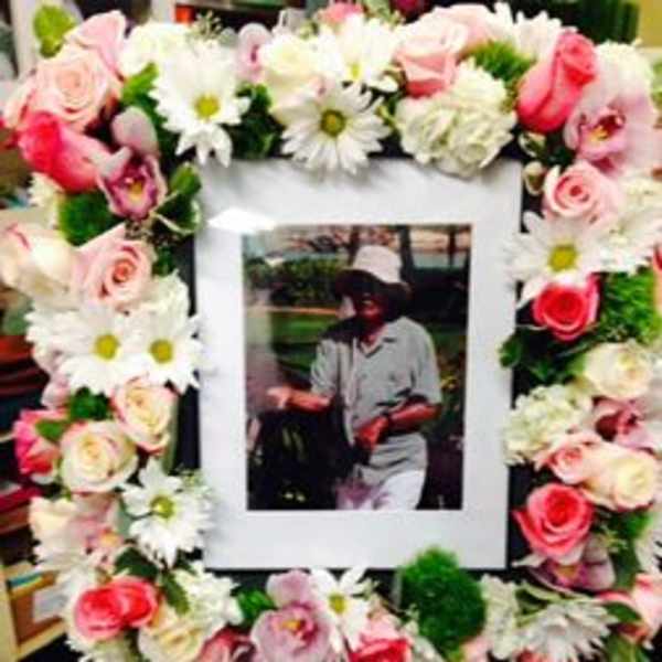 Flower wreath around a framed photo with pink roses and white daisies