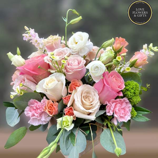 Mixed bouquet of pink and cream roses with carnations and lisianthus in a vase