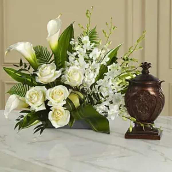 White roses and calla lilies arranged with white orchids in a dark vase