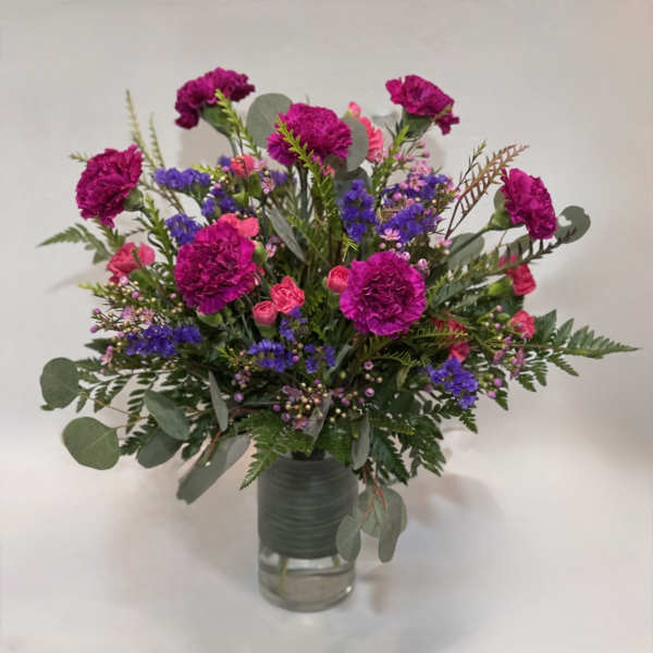 Bouquet of magenta carnations and purple filler flowers in a glass vase