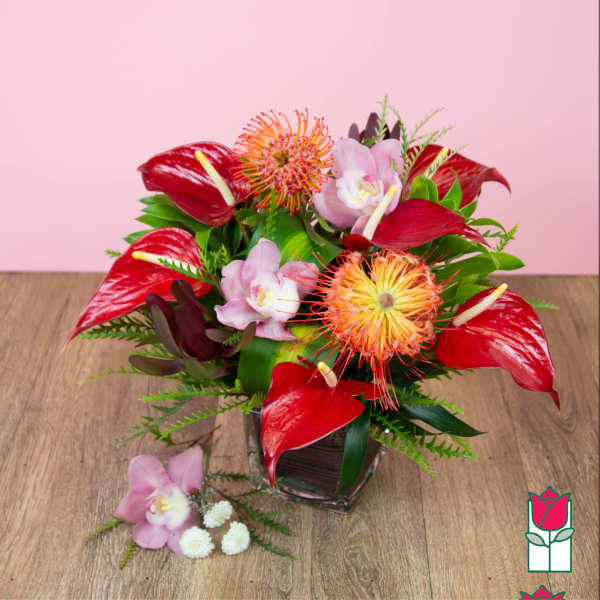 Red anthuriums and pink orchids arranged in a glass vase