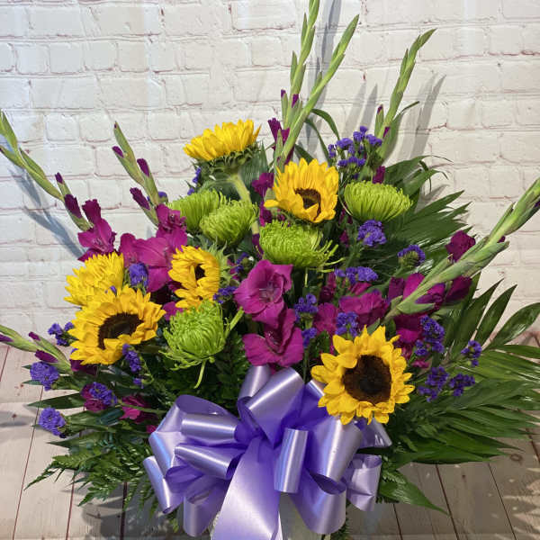 Bright mixed bouquet with sunflowers, purple flowers, and a lavender ribbon