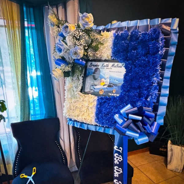 Blue and white floral funeral tribute with ribbon and photo centerpiece