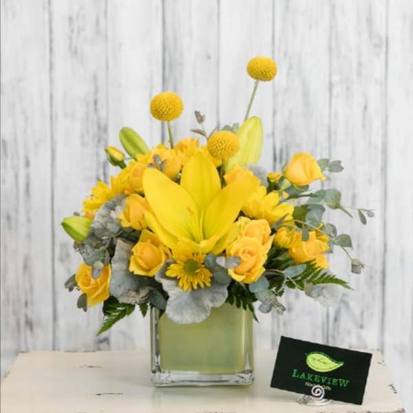 Yellow floral arrangement in a square glass vase