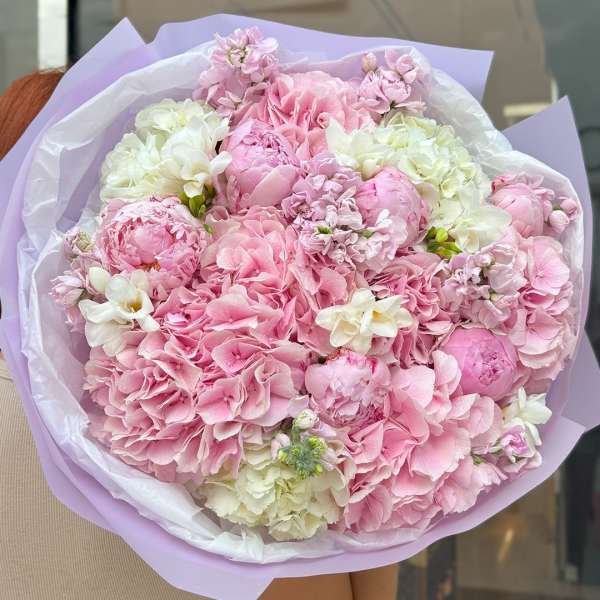 Bouquet of pink and white flowers wrapped in lavender paper