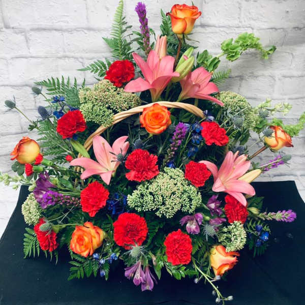 Large mixed floral arrangement with pink lilies, red carnations, and orange roses