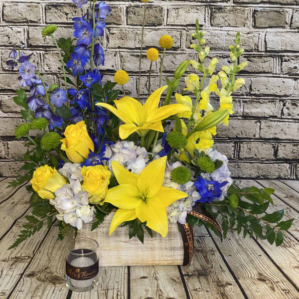 Yellow lilies and roses with blue flowers in a wooden box